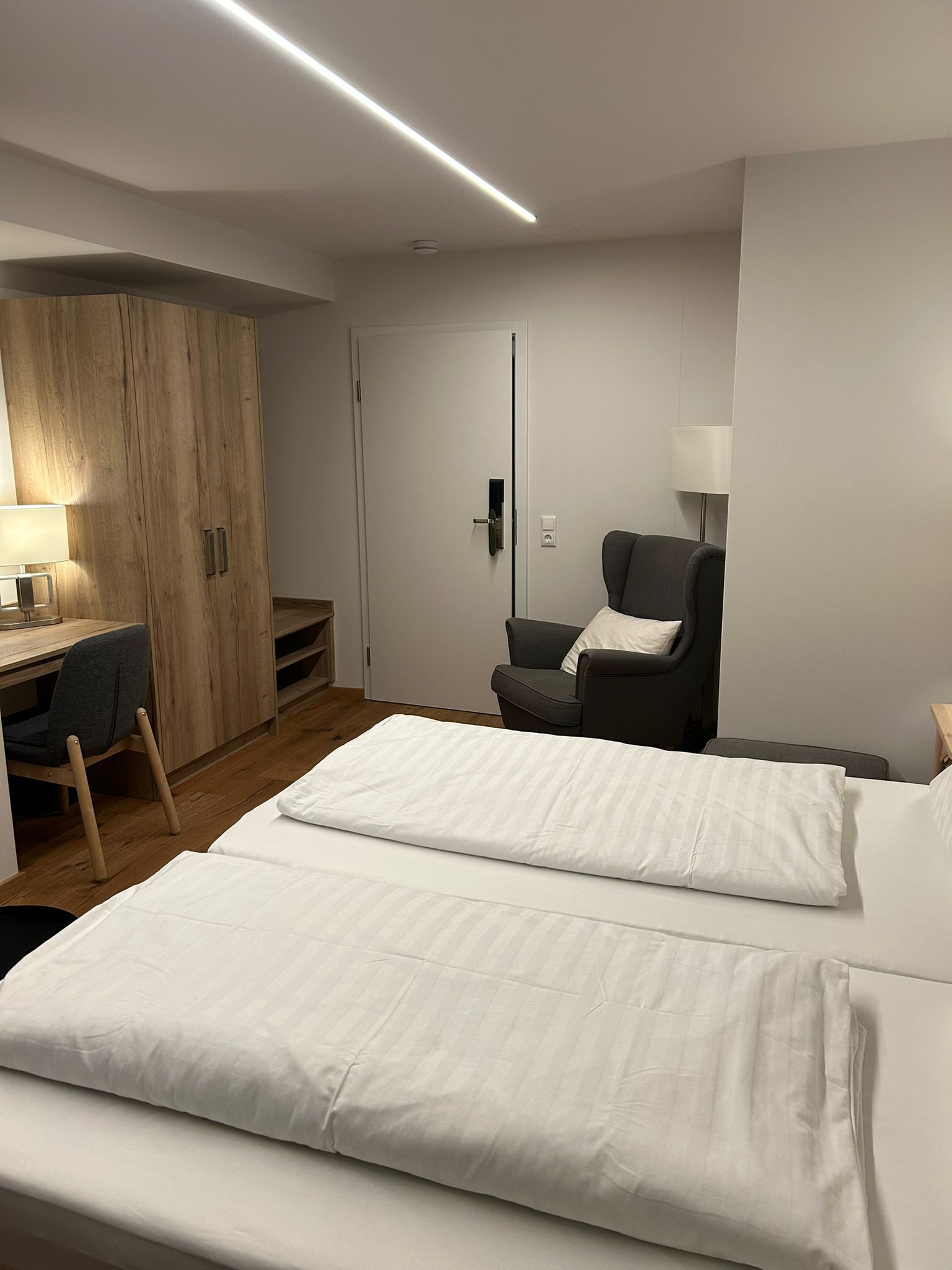 Ein Hotelzimmer mit Bett, Schreibtisch, Stuhl und Kleiderschrank.