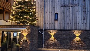 A building with a wooden facade, a Christmas tree with lights, and a sign reading 'Landhotel.'