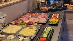 A buffet with various food items, including meats, cheeses, and vegetables.