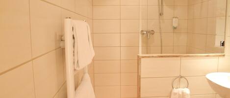 Une salle de bain avec une douche, un lavabo et un porte-serviettes.