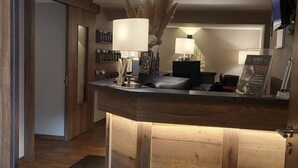 A reception area with a wooden counter, a door to a room, and a ceiling with a perforated pattern.