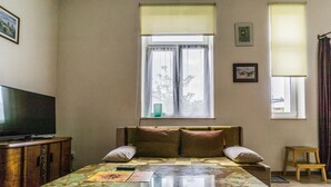 Ein Zimmer mit einem Bett, einem Fernseher und einem Vorhangfenster.