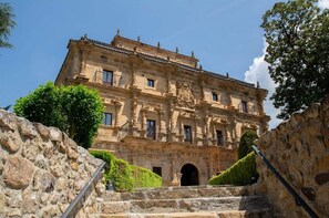 Un edifici històric amb una entrada imponent, escales de pedra i un balcó.