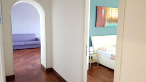 A hallway with a purple sofa and a white bed with a striped blanket. - S. PETER - BIG APARTMENT IN FRONT OF DOME WITH VIEW (Roma)