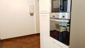 A kitchen with white cabinets, a microwave, and an oven. - S. PETER - BIG APARTMENT IN FRONT OF DOME WITH VIEW (Roma)