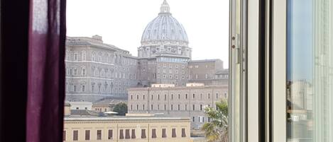 A view of a large building with a prominent dome, likely a government or historical building, seen through a window with a curtain.