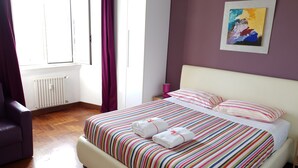 A bedroom with a bed, a chair, a radiator, a window, and a painting on the wall. - S. PETER - BIG APARTMENT IN FRONT OF DOME WITH VIEW (Roma)