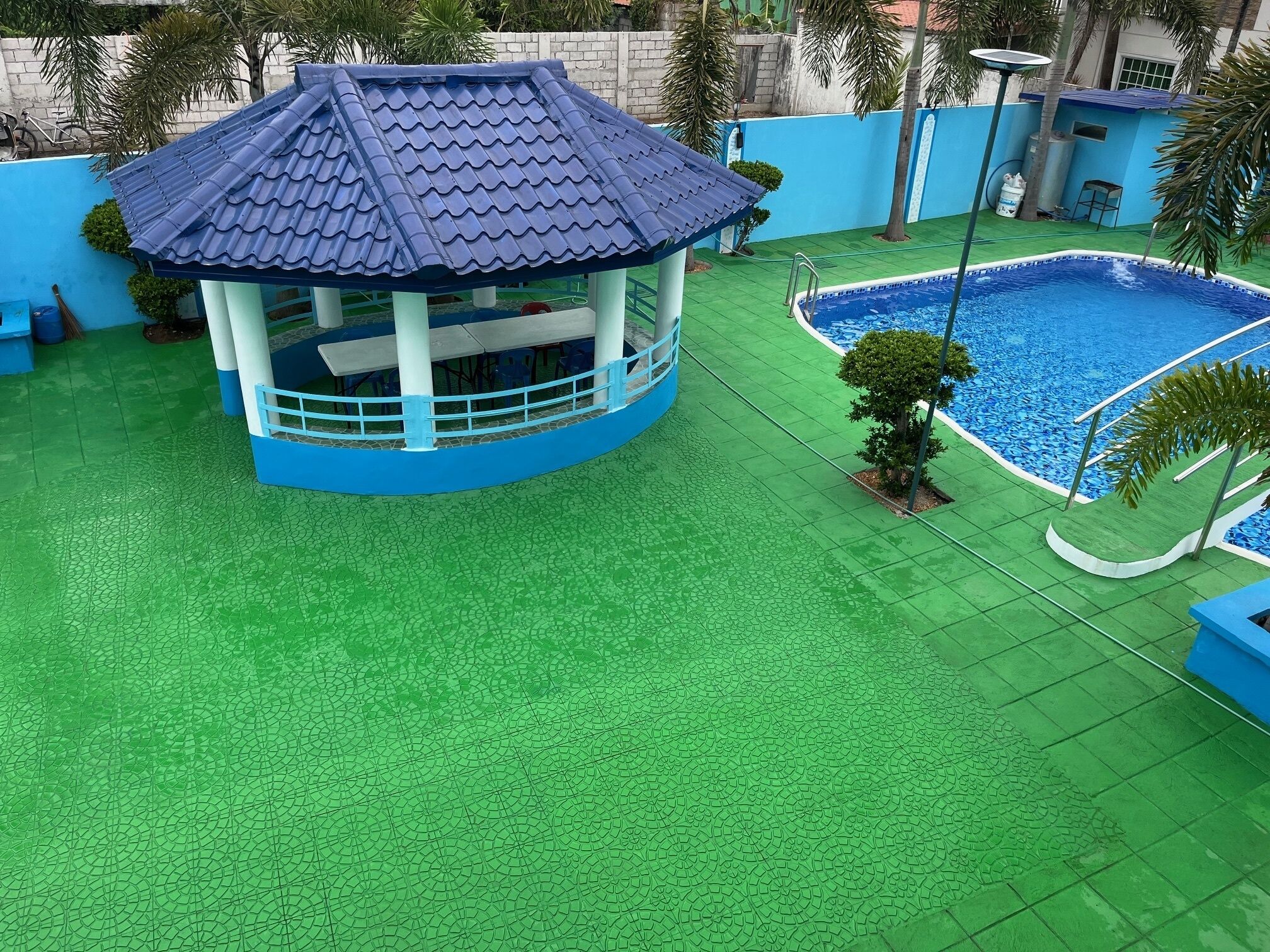 Ein überdachter Pavillon mit Ziegeldach, einem Schwimmbad und grünem Kunstrasen.