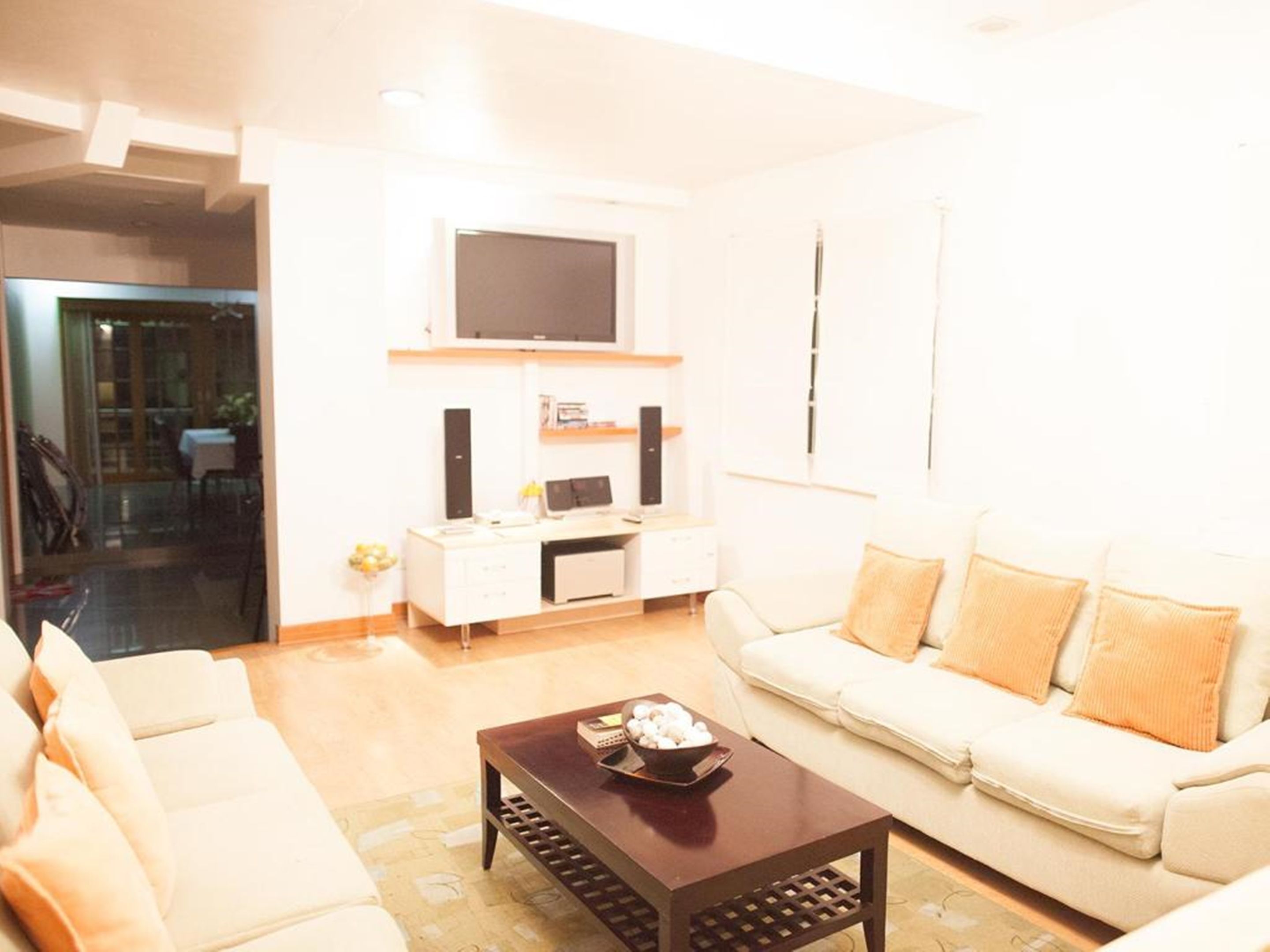 A modern living room with a white sofa, a coffee table, and a TV mounted on the wall.