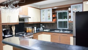 A modern kitchen with wooden cabinets, a black countertop, and a stainless steel refrigerator. - Sir Nico Guesthouse and Resort (Plaridel)