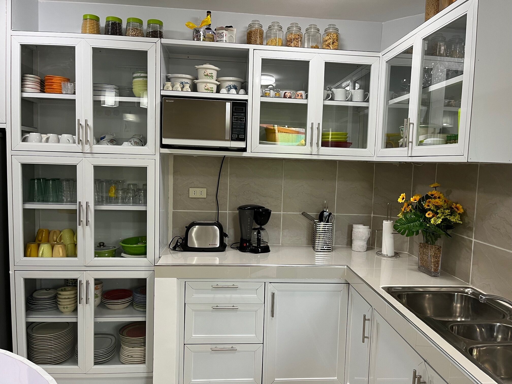 A modern kitchen with white cabinetry, a built-in microwave, and a stainless steel sink.