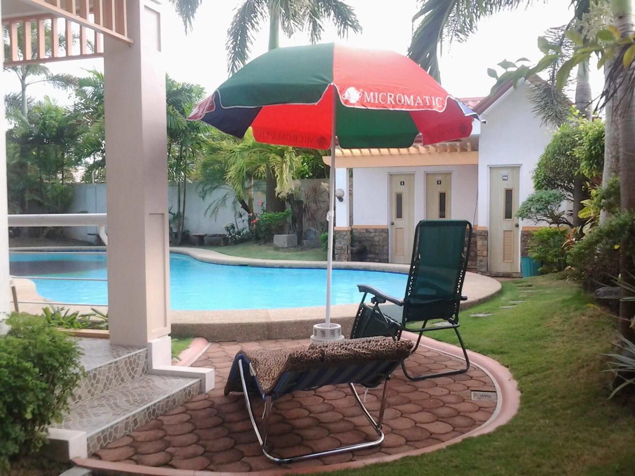 A poolside area with a lounge chair and an umbrella.