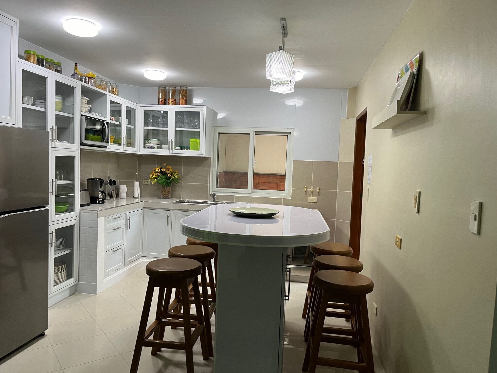 Una cocina moderna con armarios blancos, una isla central con taburetes y un horno empotrado.