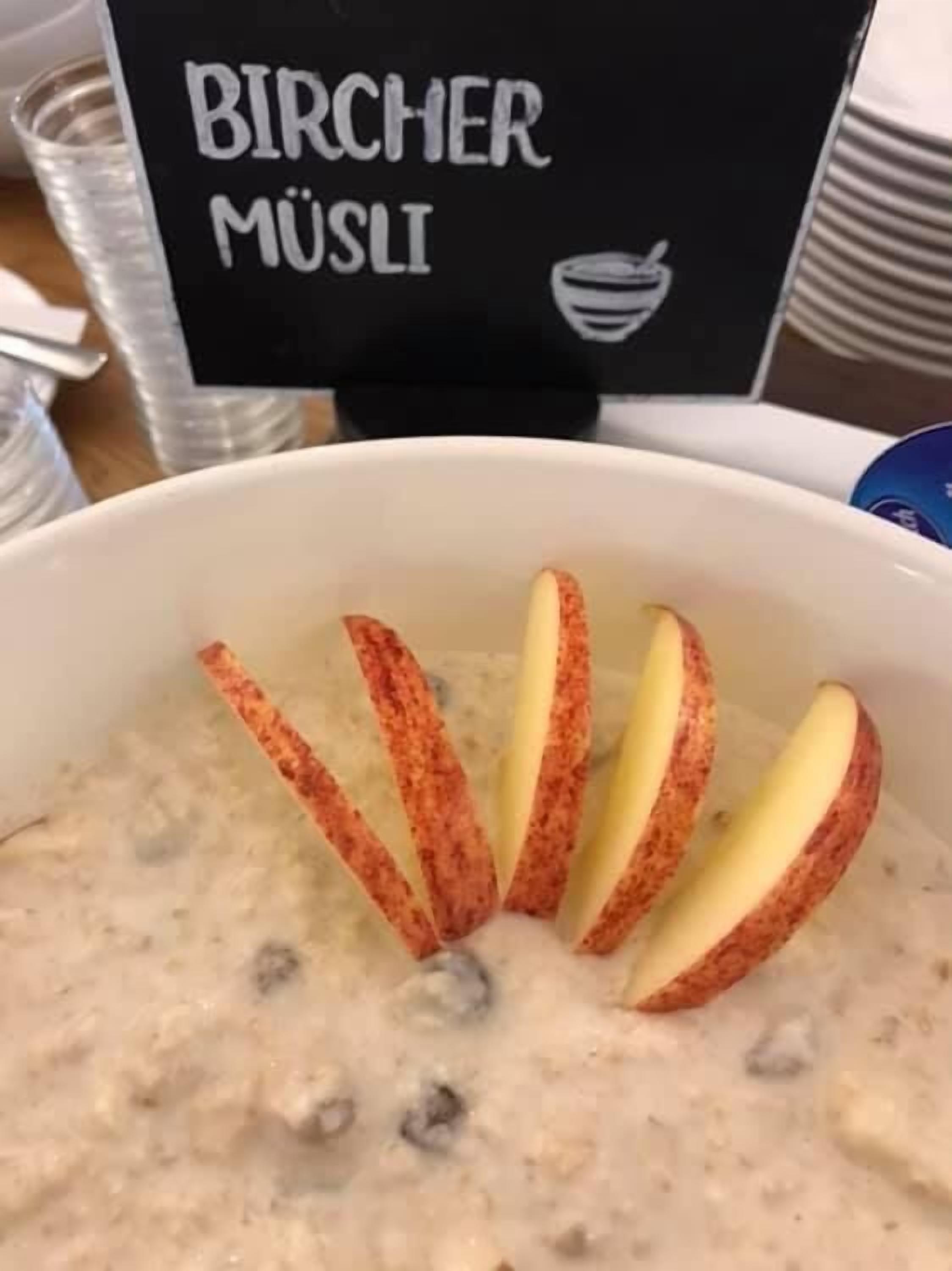 Uma tigela de comida cremosa com fatias de maçã dispostas por cima.