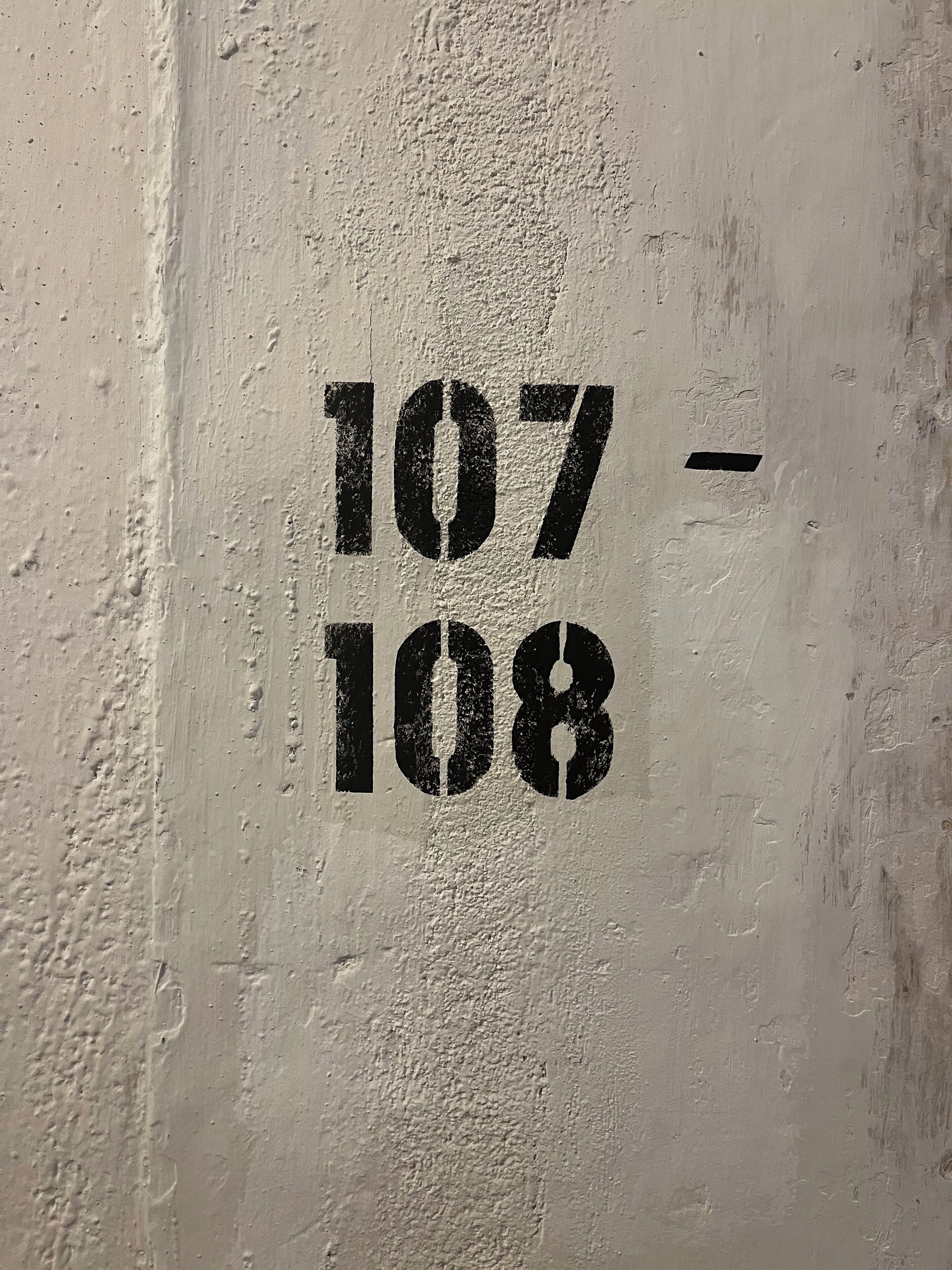 A wall with the numbers "107 - 108" painted on it.