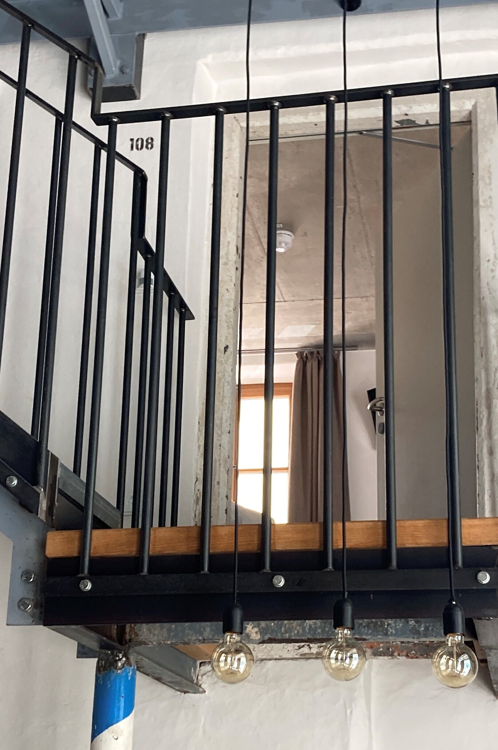 A staircase with black metal railings and a wooden handrail, leading to an upper floor.