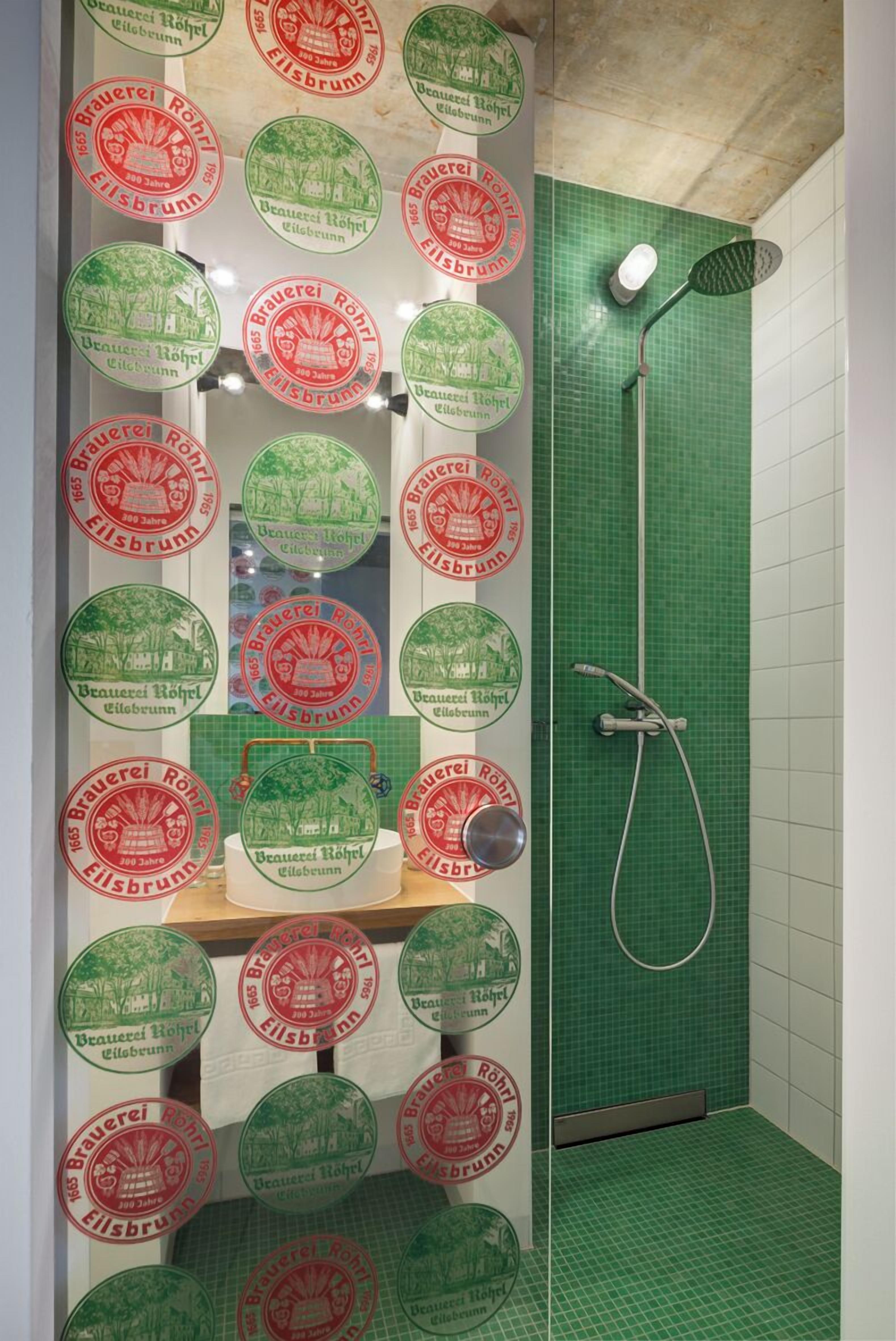 Une salle de bain avec des murs recouverts de carreaux verts, une douche et plusieurs miroirs ronds ornés de motifs rouges et verts.