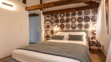 Une chambre à coucher avec un lit, des poutres en bois, un mur à motifs et un radiateur.