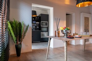 A modern kitchen with dark cabinetry, a microwave, and a dining area with a wooden table and chairs. - La Finestra sulle Beccarie (Venice)