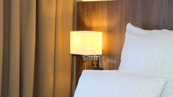 A hotel room with a bed, a nightstand with a lamp, and curtains.