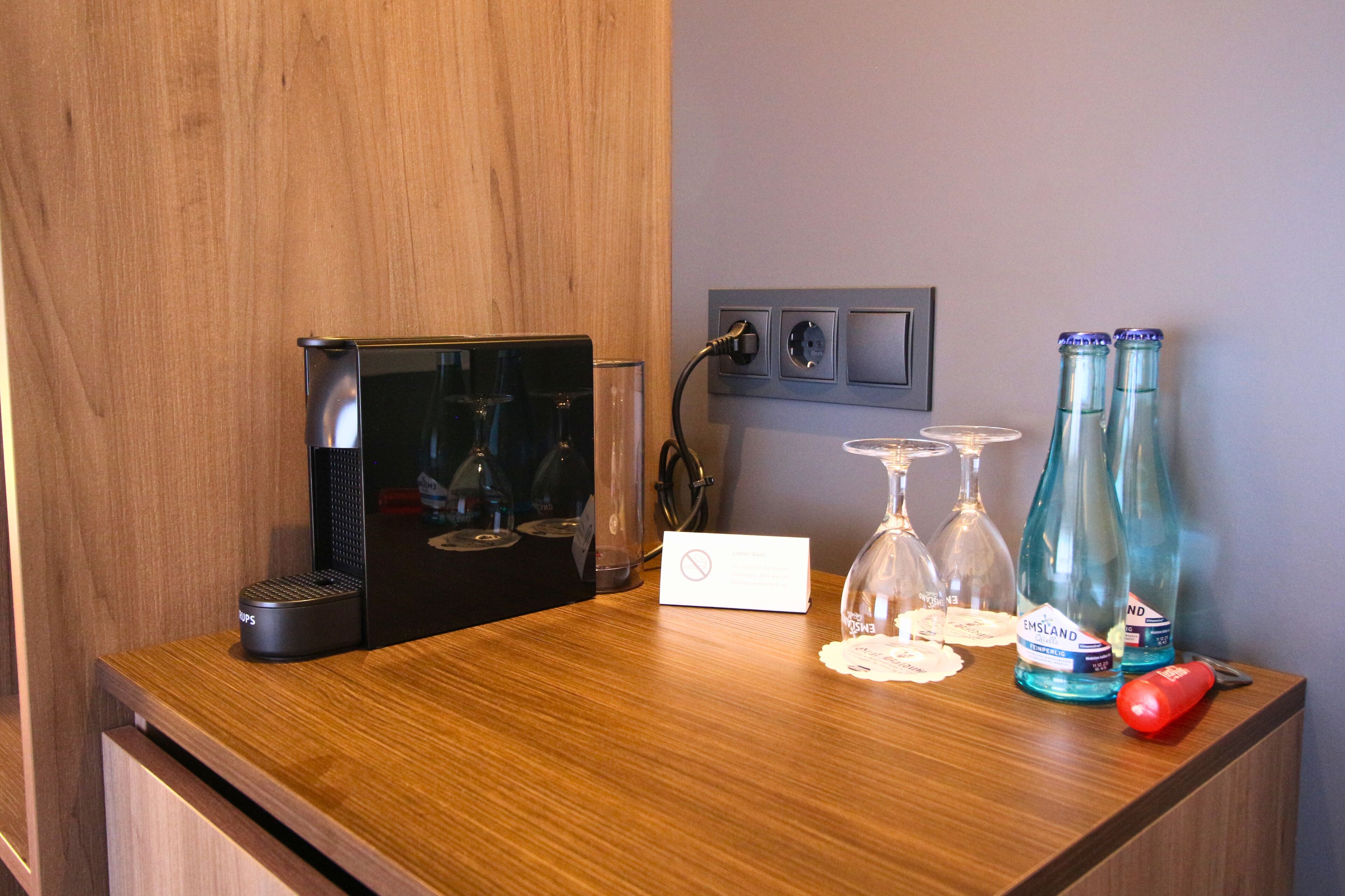 Una encimera de madera con una máquina de café, un lector de tarjetas y dos botellas de agua.