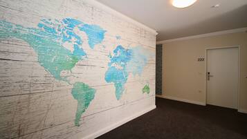 A hallway with a large world map mural on the wall, a door labeled "222", and a carpeted floor.