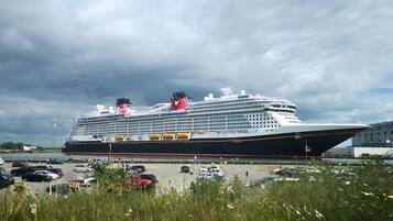 A large cruise ship docked at a port with a cloudy sky in the background.