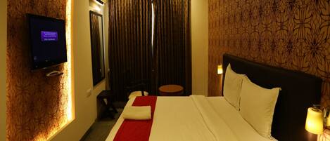 A hotel room with a bed, a television, a desk, and a chair.