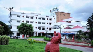 A hotel with a white facade, multiple floors, and a central entrance with a red statue. - DFRONT Golden Palace (Namakkal)