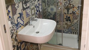 A bathroom with a sink, shower, and tiled walls. - B&B Laura e Chiara (Trapani)
