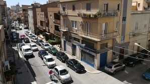 A narrow urban street lined with multi-story residential buildings, parked cars, and a visible storefront. - B&B Laura e Chiara (Trapani)