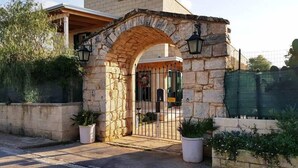 A stone building with an arched entrance, potted plants, and a gated driveway. - Casa Borgo Regina B&B Bari (Noicattaro)