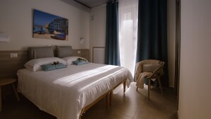 A hotel room with a large bed, a chair, a painting on the wall, and a window with curtains. - Casa Borgo Regina B&B Bari (Noicattaro)