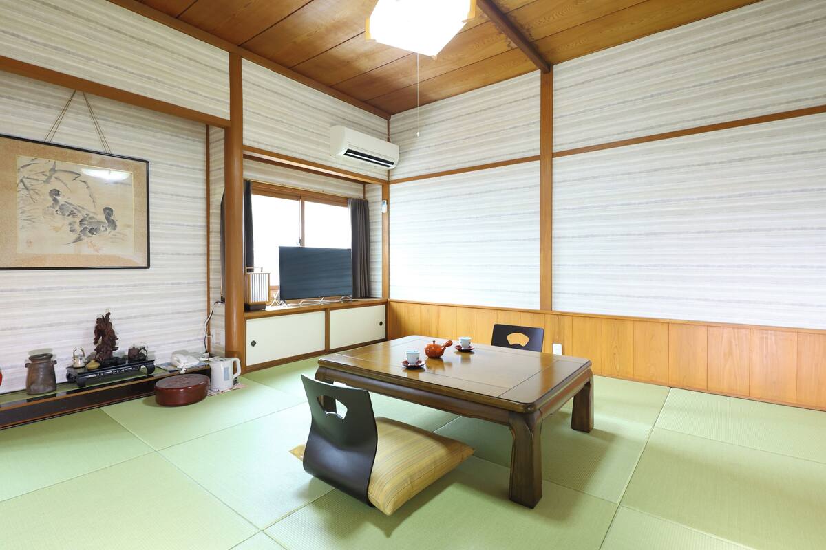 Una habitació japonesa tradicional amb sòls de tatami, una taula baixa i una porta corredissa.
