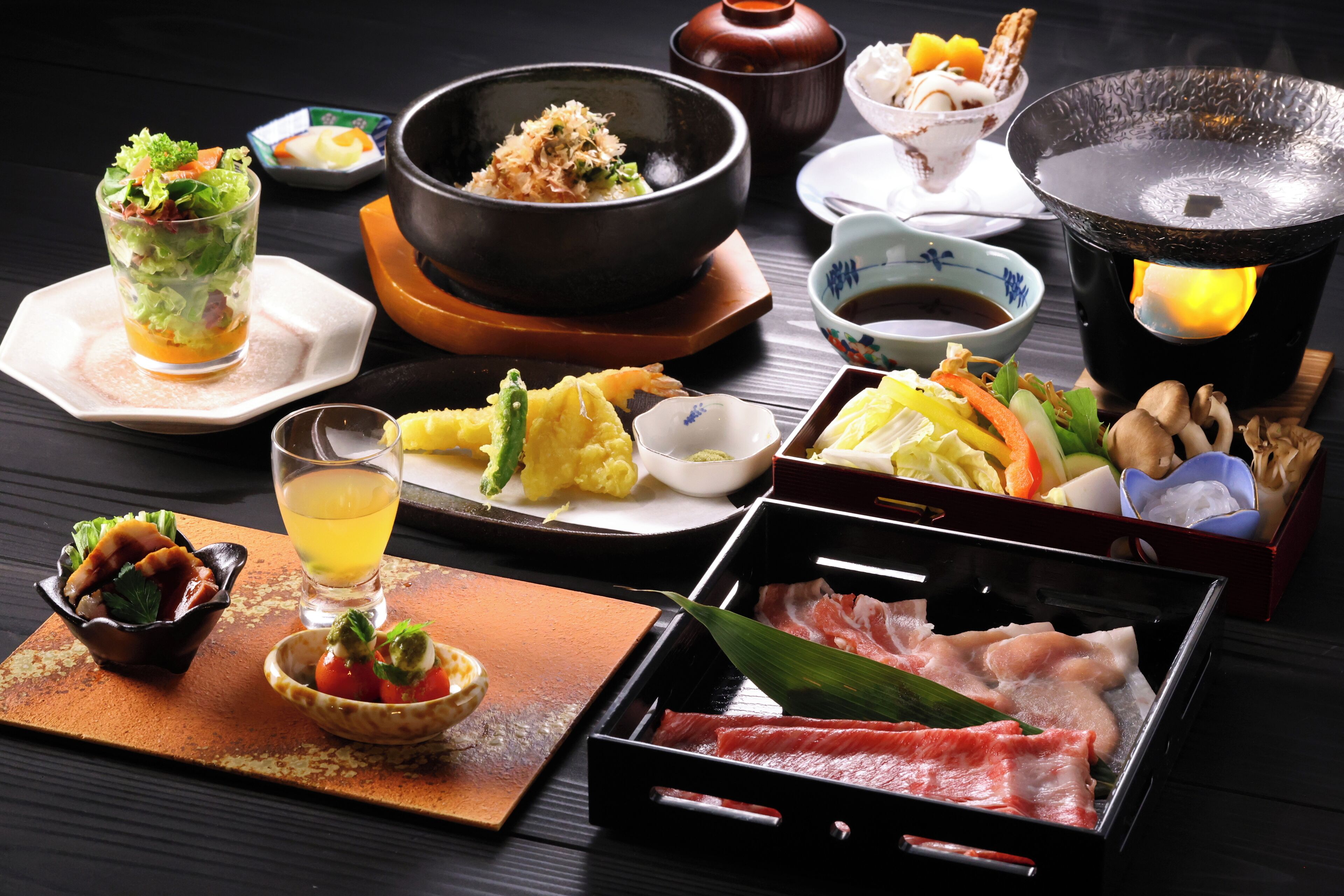 Variedad de platos japoneses, incluyendo sashimi, verduras y una olla caliente.