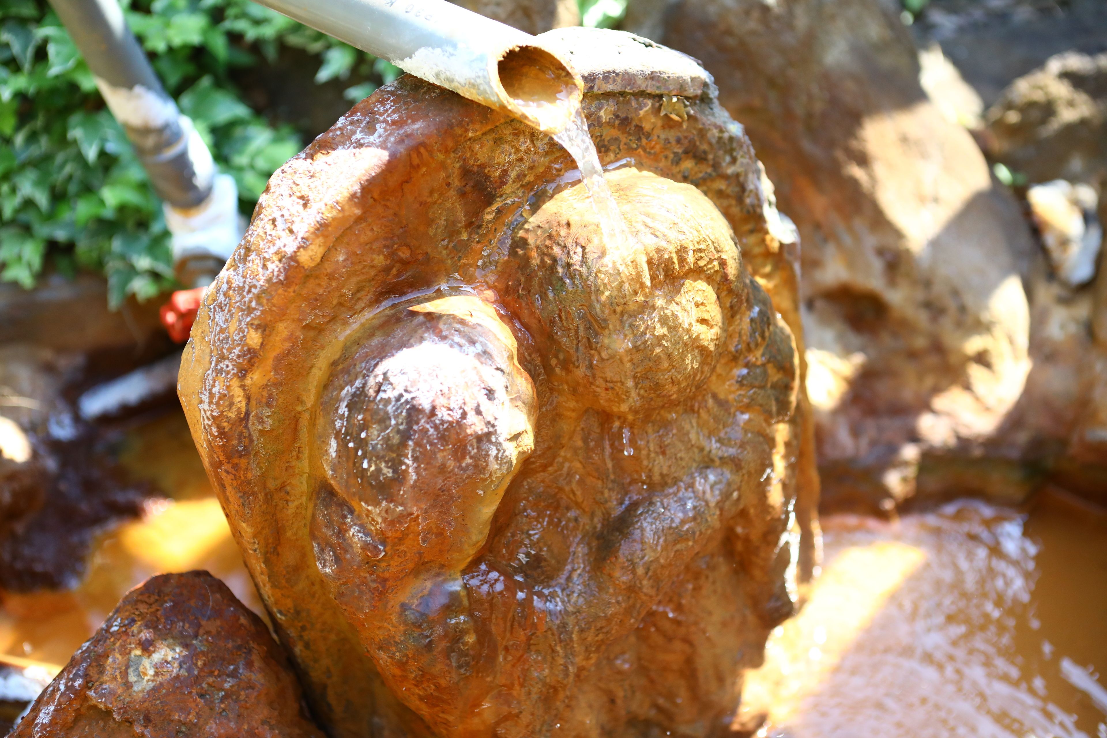 A close-up of a rustic stone structure with a pipe pouring water.