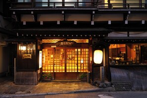 A traditional Japanese building with a wooden entrance, a signboard, and a lantern. - Ikariya Ryokan (Yamanouchi)