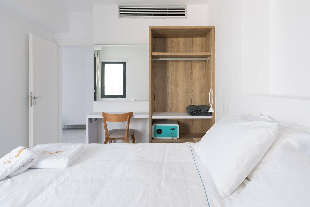 A bedroom with a bed, a desk, a chair, and a wardrobe.