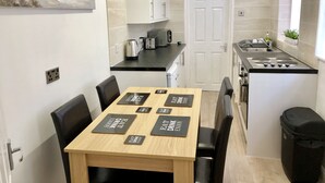 Une cuisine compacte comprenant une table à manger, des chaises, une cuisinière et une machine à café.