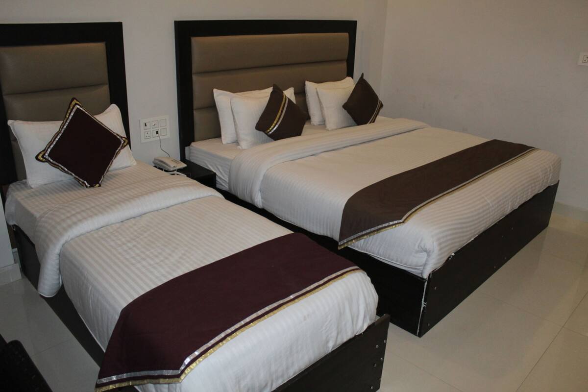 Two twin beds with headboards, a bedside telephone, and a brown throw blanket.