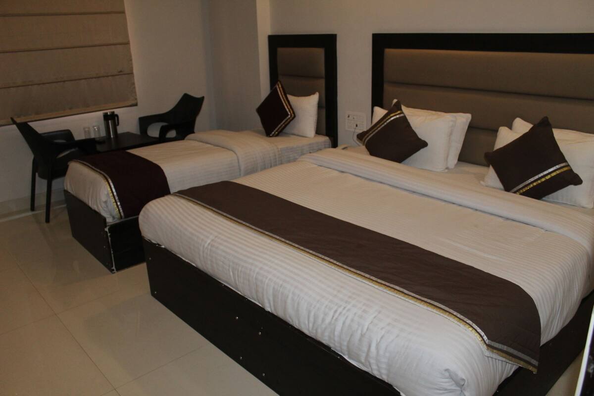 A hotel room with two beds, a desk, and a chair.