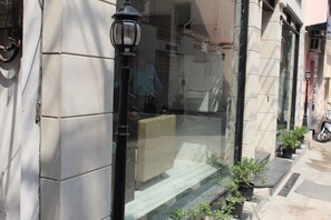 Un bâtiment à l’extérieur recouvert de tuiles, un lampadaire noir et des plantes en pot disposées au sol.