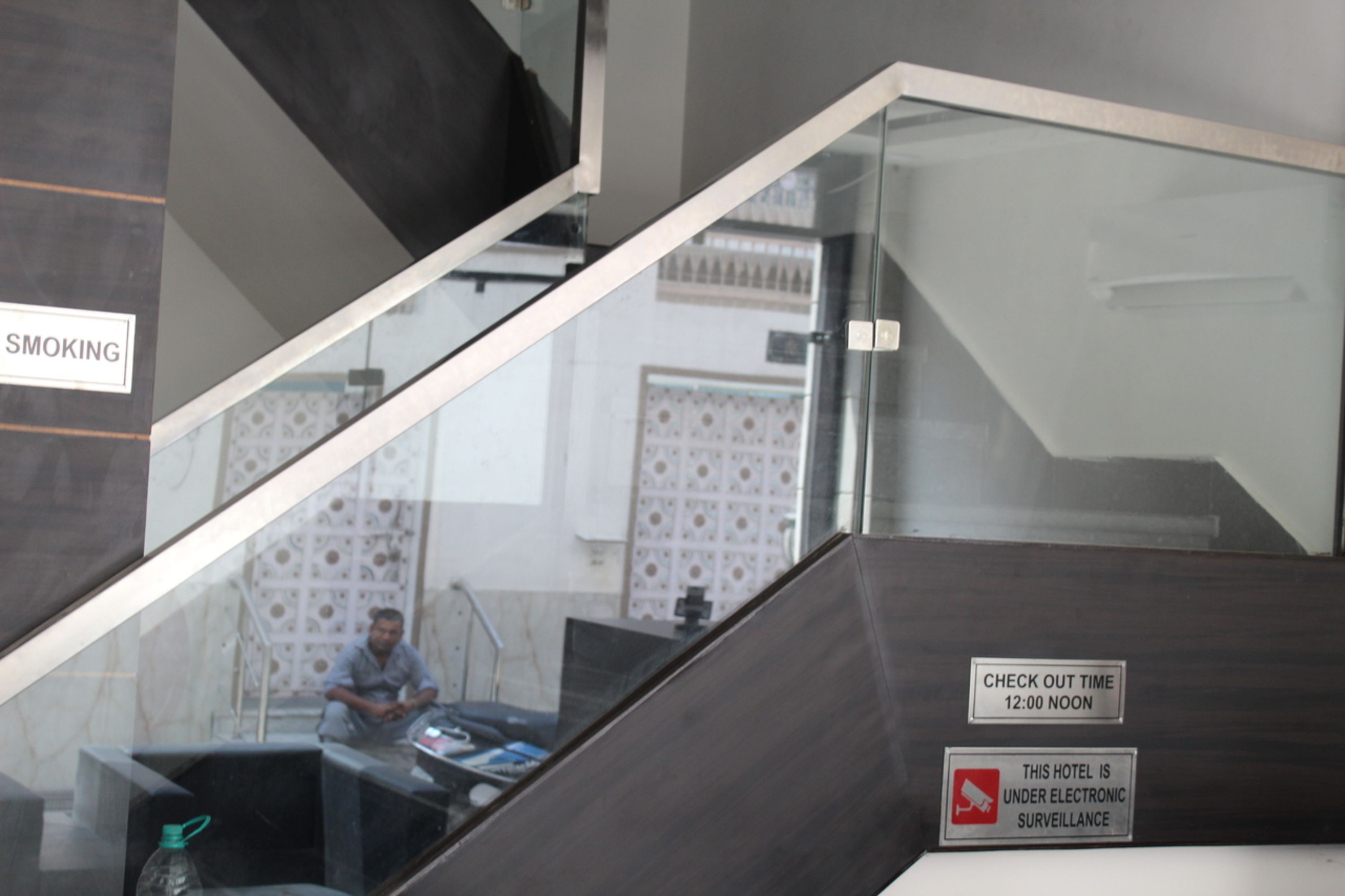 A hotel interior with a check-out time sign, a smoking sign, and a notice about electronic surveillance.