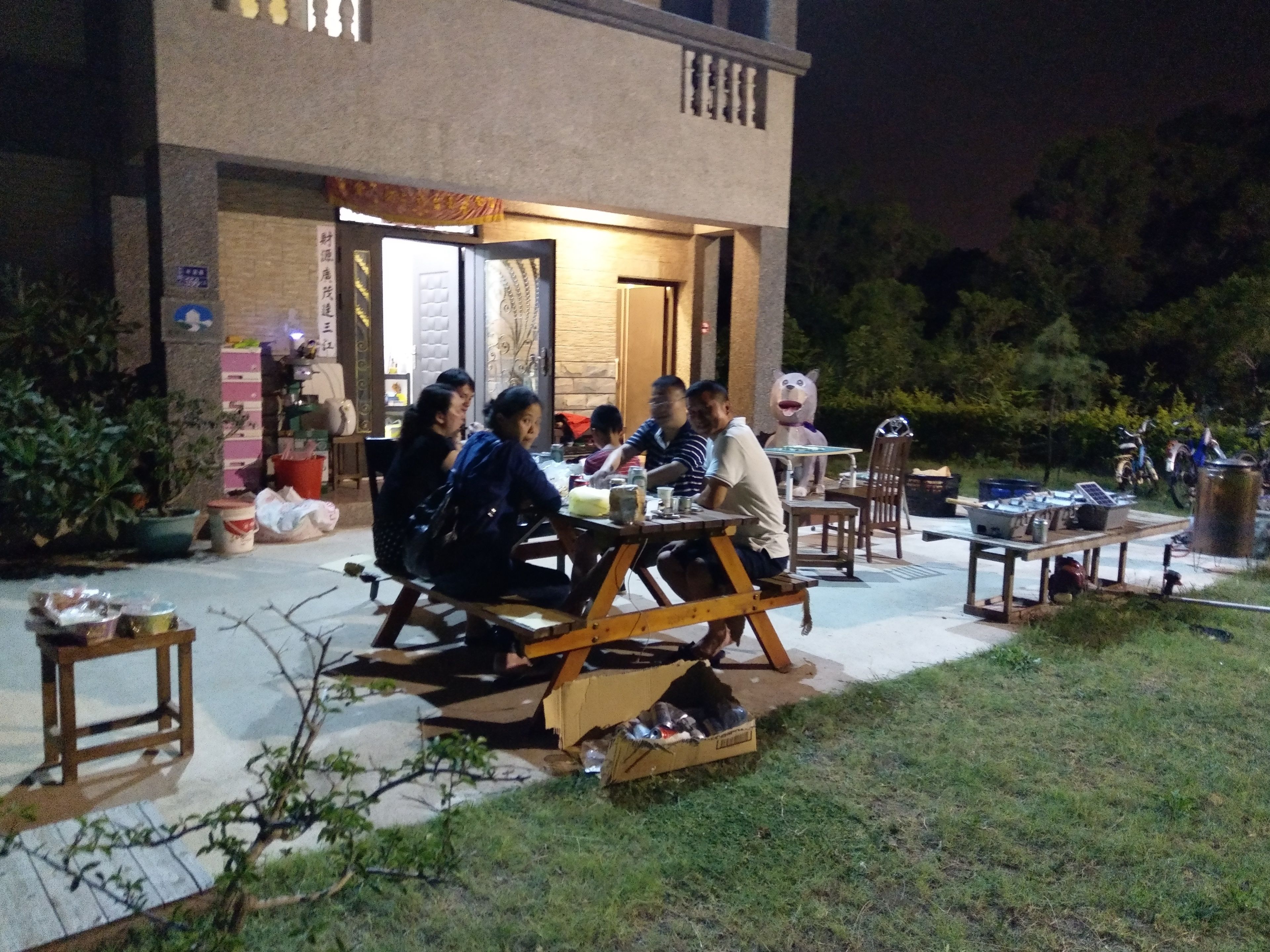 Un grupo de personas cenando al aire libre en un restaurante con fachada de ladrillo y terraza de madera.