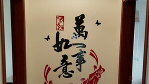 Un pasillo con una lámpara en el techo, un extintor y una pared con caligrafía china y obra de arte roja.