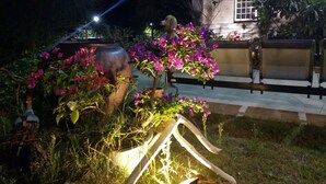 Un jardín con una jardinera grande, un banco y un edificio al fondo.
