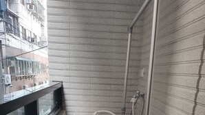 A compact, white, wall-mounted washer and dryer unit in a narrow bathroom with tiled walls and a wooden floor. - Donghae13.8 (Taichung)