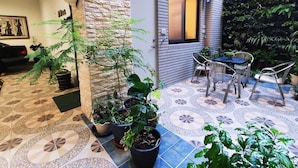 A patio area with a stone wall, tiled floor, and potted plants. - Donghae13.8 (Taichung)