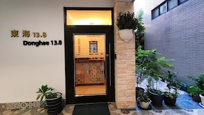 A hotel entrance with a tiled floor, a black door, and a sign indicating the name and address. - Donghae13.8 (Taichung)