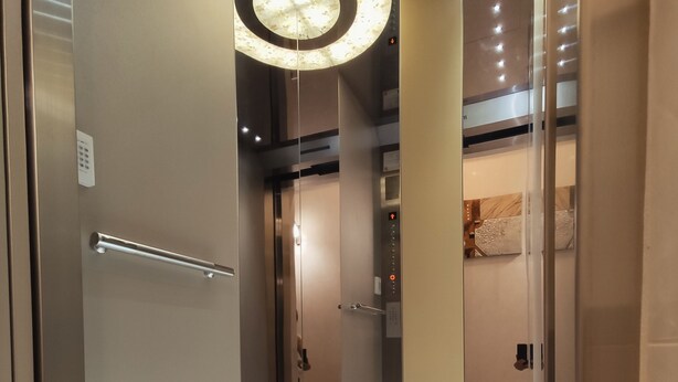 A modern elevator interior with a marble floor and a circular light fixture. - Donghae13.8 (Taichung)